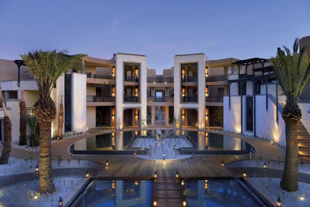 Luxuriöse Hotelarchitektur mit beleuchtetem Pool bei Sonnenuntergang