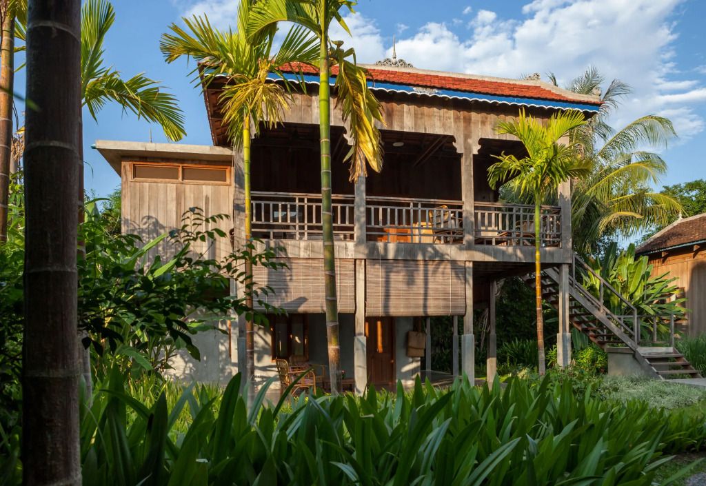 Traditionelles Holzgebäude mit Pflanzen und Palmen im Vordergrund