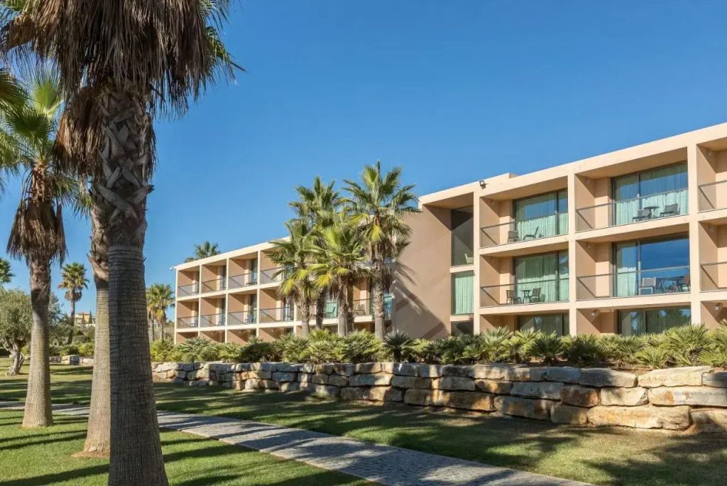 Außenansicht des Hotels mit Palmen und blauen Himmel
