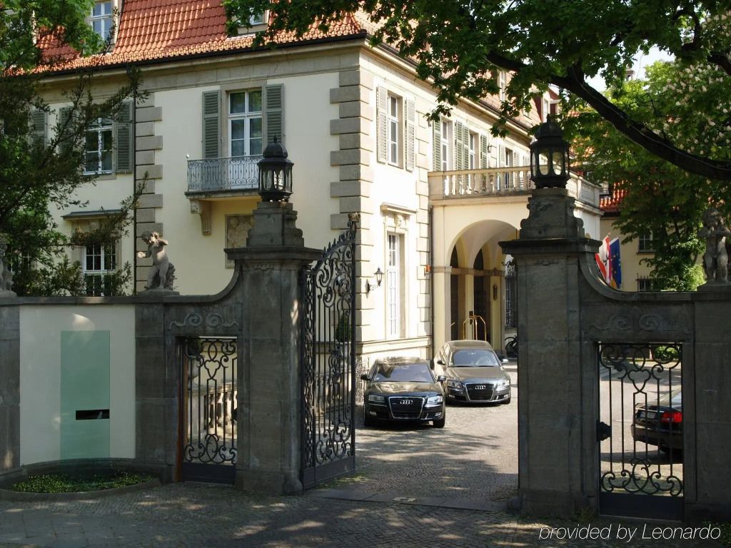 Elegante Fassade des Schlosshotels mit geöffneter Eingangspforte und Limousinen