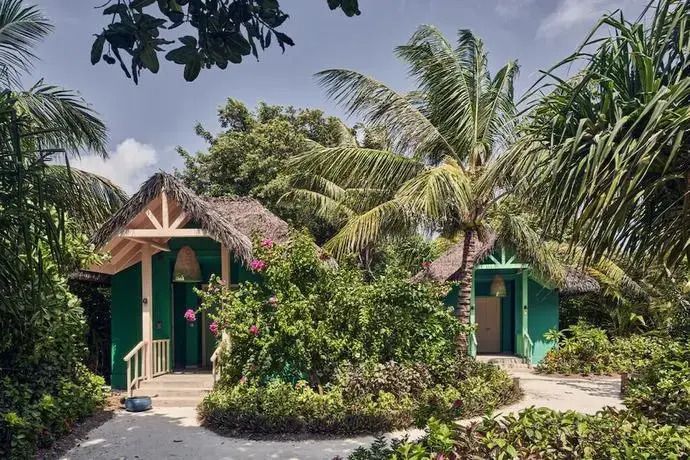 Tropisches Bungalow im Grünen mit Palmen und reicher Vegetation.