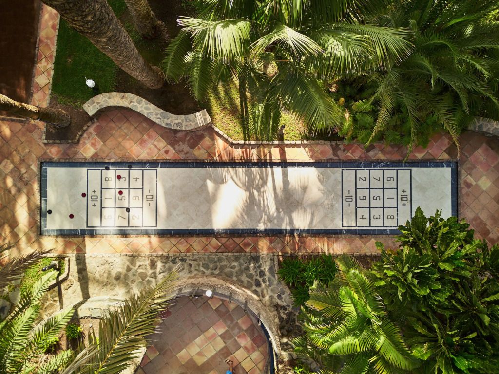 Shuffleboardplatz im tropischen Garten des Hotels umgeben von Palmen.