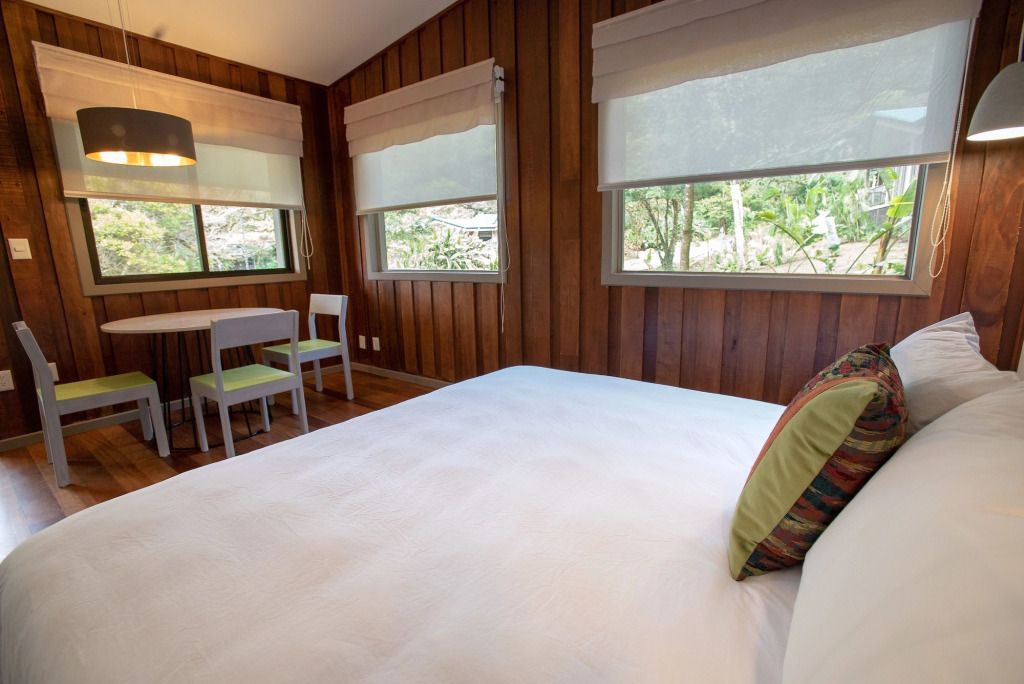 Holzgetäfeltes Hotelzimmer mit großem Bett und Ausblick auf Wald