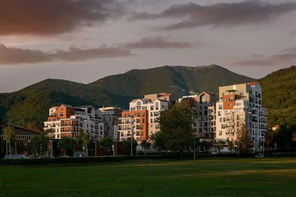 Moderne Hotelanlage vor bewaldeten Bergen mit Wolken am Himmel
