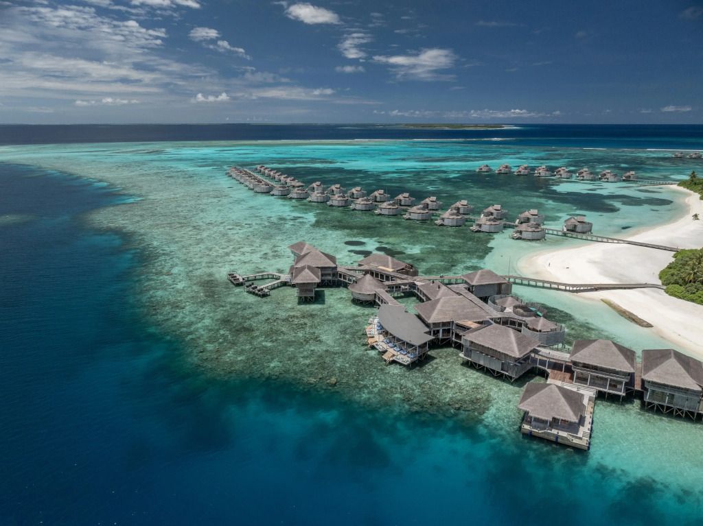 Luftaufnahme von Overwater-Villen auf türkisfarbenem Wasser im Six Senses Laamu