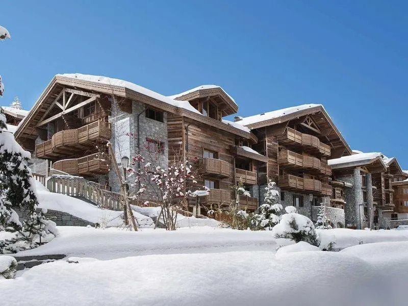 Schneebedeckte Fassade der Six Senses Residences Courchevel vor blauem Himmel