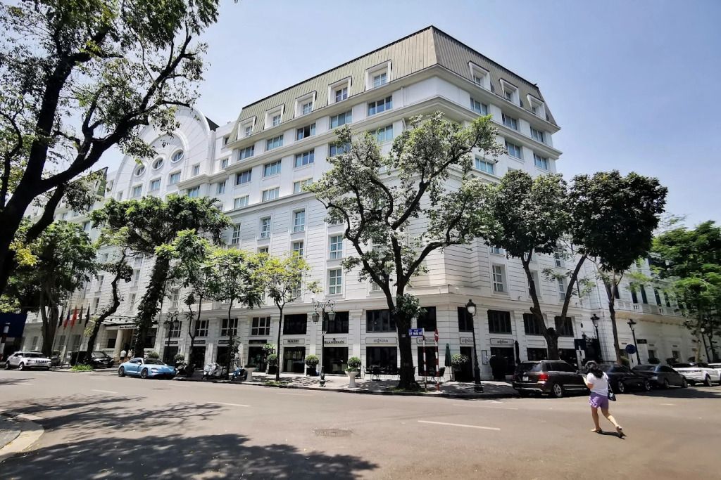 Elegante Fassade des Sofitel Legend Metropole Hanoi mit Bäumen im Vordergrund
