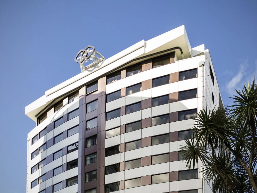 Moderne Fassade des Sofitel Wellington mit ikonischem Logo gegen blauen Himmel