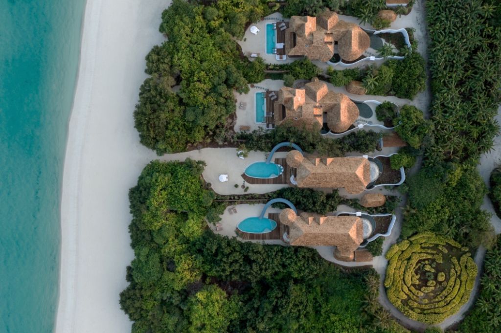 Luftbild von Villen mit Pools am Strand umgeben von grüner Vegetation