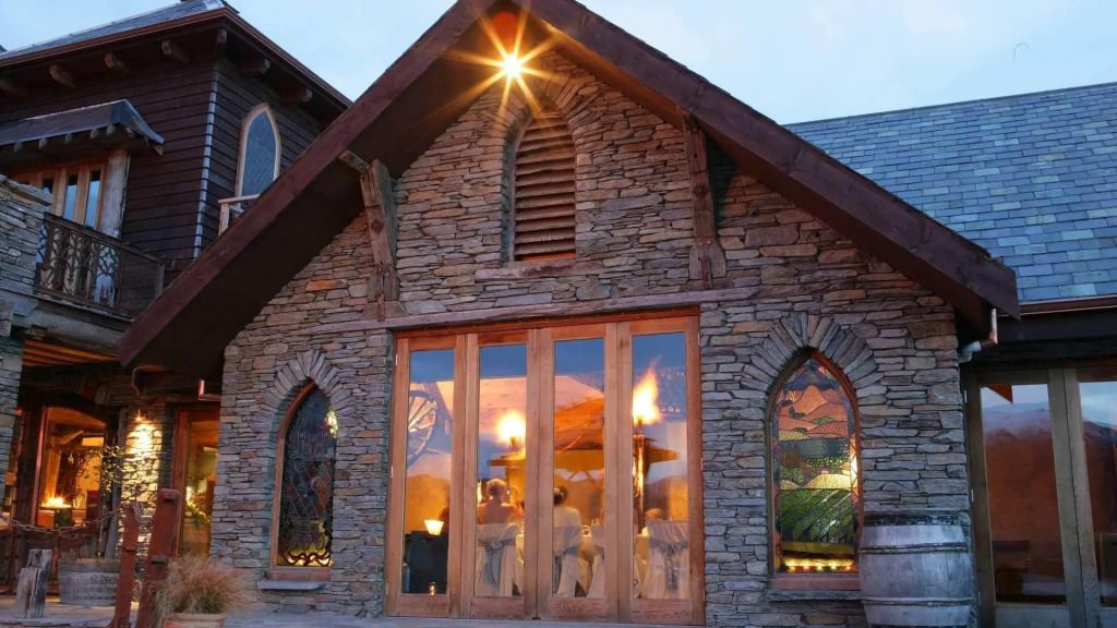 Rustikales Steingebäude mit großen Fenstern bei Dämmerung