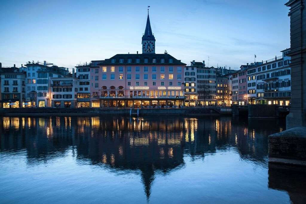 Beeindruckende Fassade des Storchen Zurich Hotels am Fluss bei Dämmerung