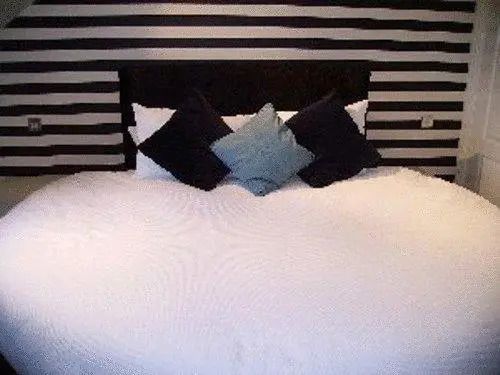 Modernes Schlafzimmer mit gestreifter Wanddekoration und gemütlichem Bett