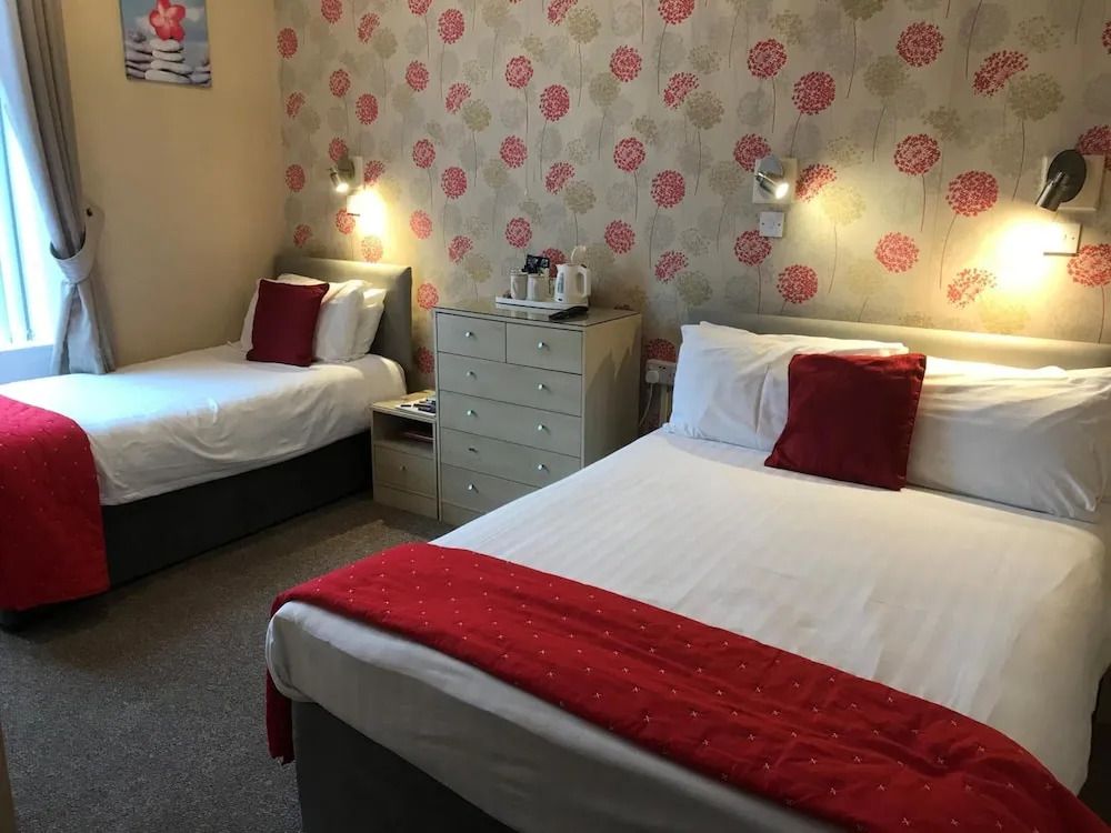 Gemütliches Hotelzimmer mit zwei Betten und roter Akzentdecke