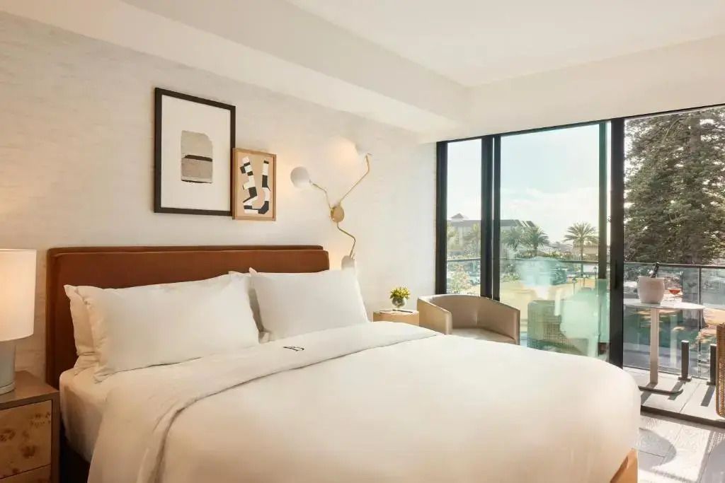 Elegantes Hotelzimmer mit großem Bett und Fenster mit Aussicht auf Palmen.