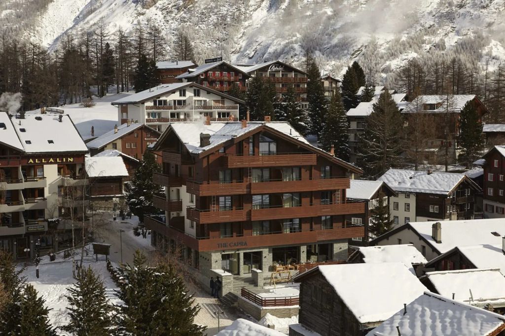 Alpenhotel im Winter mit verschneiten Dächern und umliegenden Bergen