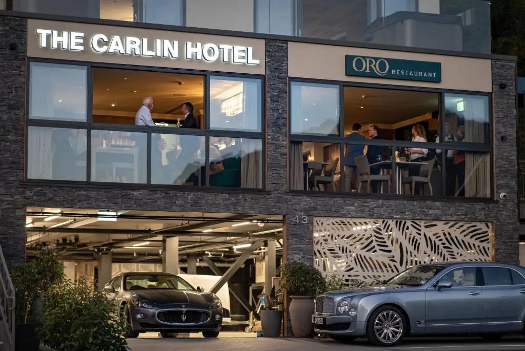 Moderne Hotelfassade mit Restaurant und parkenden Luxusautos