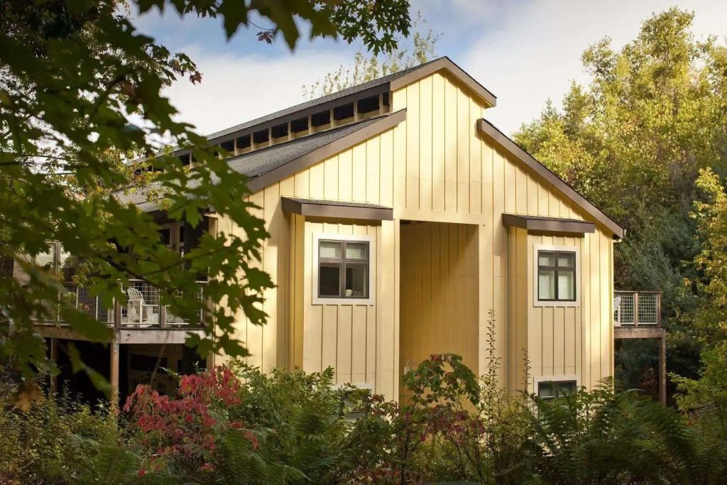 Rustikales Gebäude mit gelber Holzfassade und grüner Umgebung