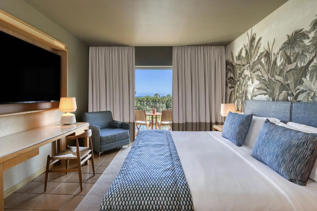 Modernes Hotelzimmer mit Balkonblick auf Palmen.