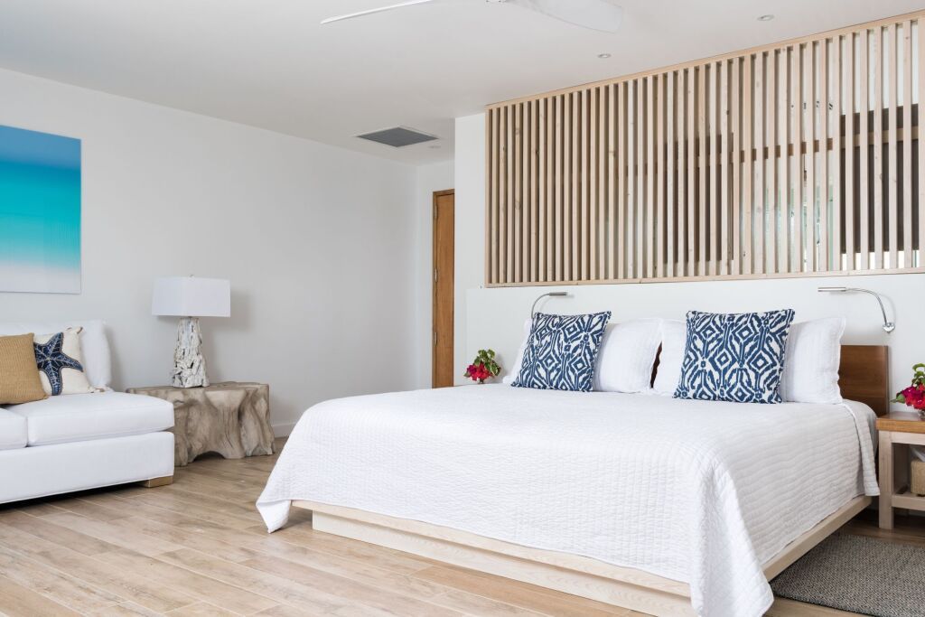 Elegantes Hotelzimmer mit weißem Bett und blauen Akzenten und Holzelementen.