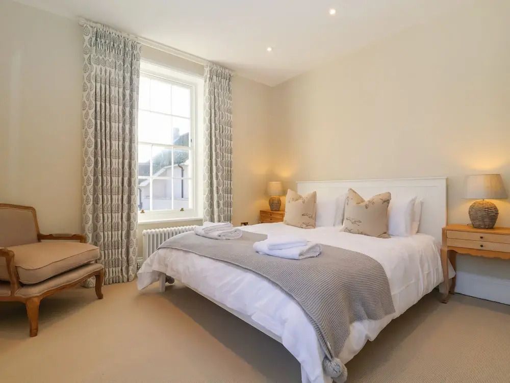 Helles Schlafzimmer mit Doppelbett und Fenstervorhängen.