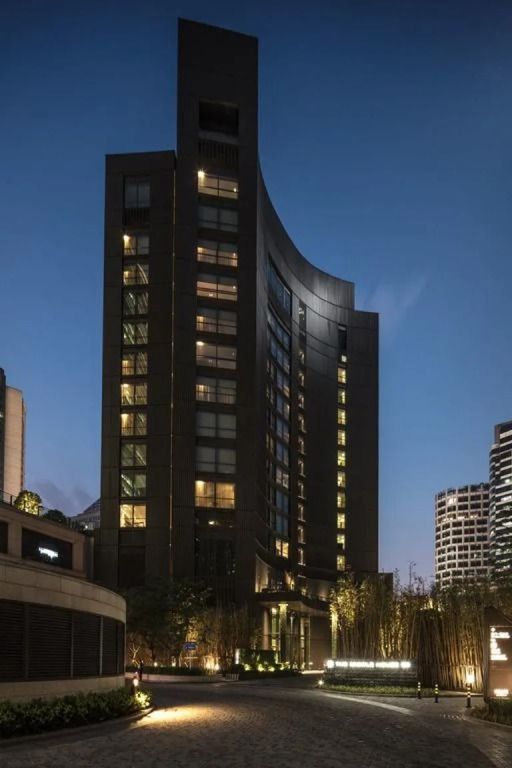 Hochhaus des Upper House Shanghai bei Abenddämmerung mit beleuchteten Fenstern