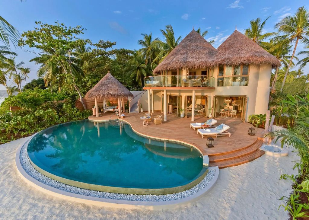 Luxuriöse Villa mit privatem Pool direkt am Strand umgeben von tropischer Vegetation.