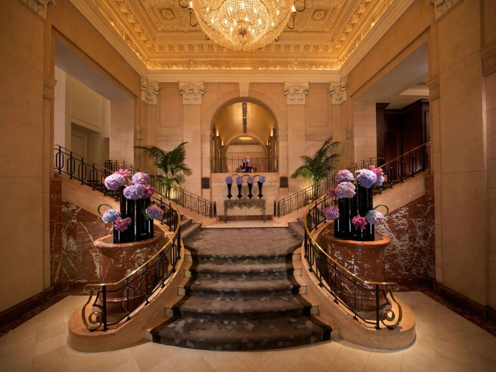 Elegante Lobby mit Kronleuchter und mit Blumen dekorierter Marmortreppe