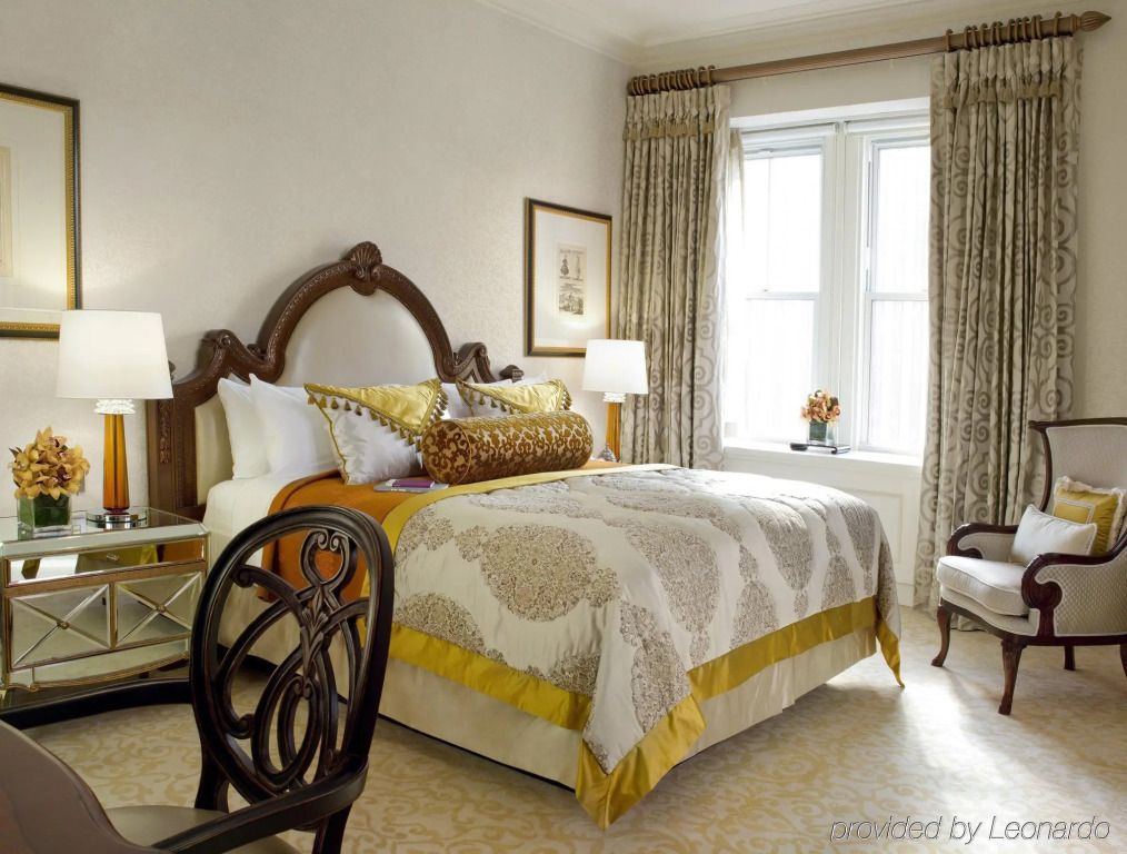 Elegantes Hotelzimmer mit reich verziertem Bett und großen Fenstern