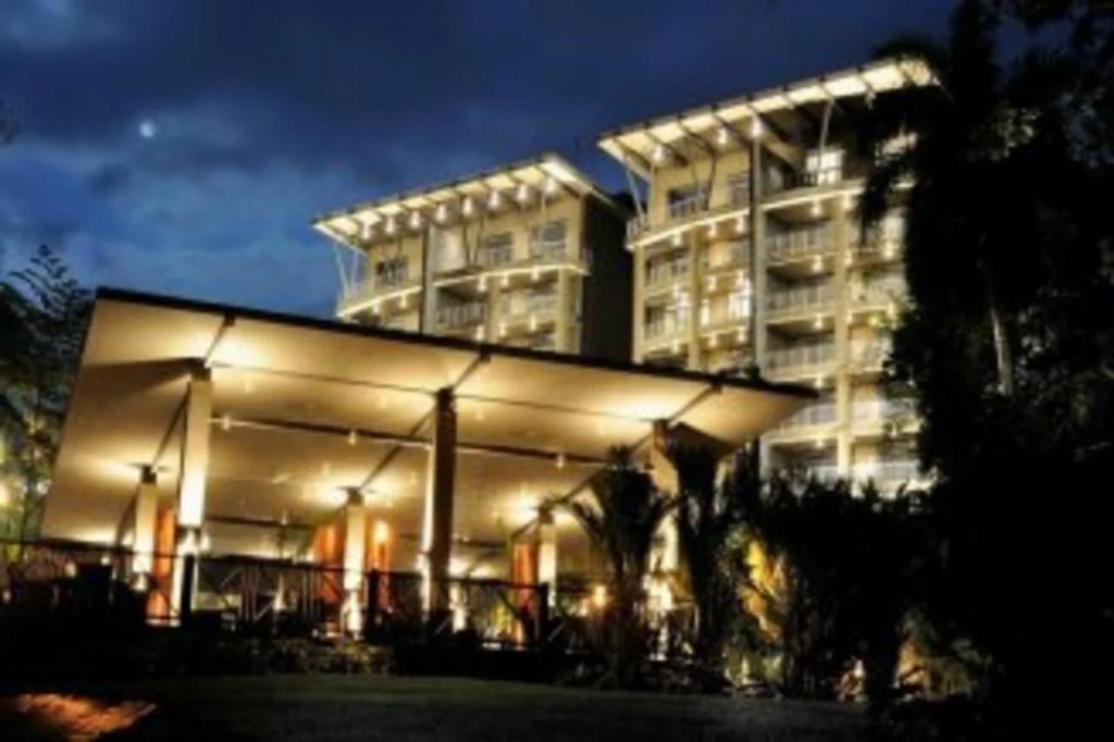 Beleuchtete Fassade des Los Altos Resort bei Nacht mit Palmen im Vordergrund