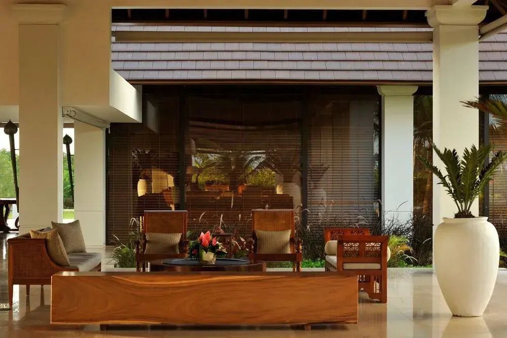 Holzmöblierte Lounge mit Ausblick ins Grüne durch große Fenster.