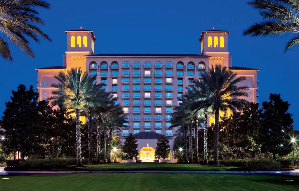 Beleuchtete Fassade des Ritz-Carlton Orlando bei Nacht umgeben von Palmen.