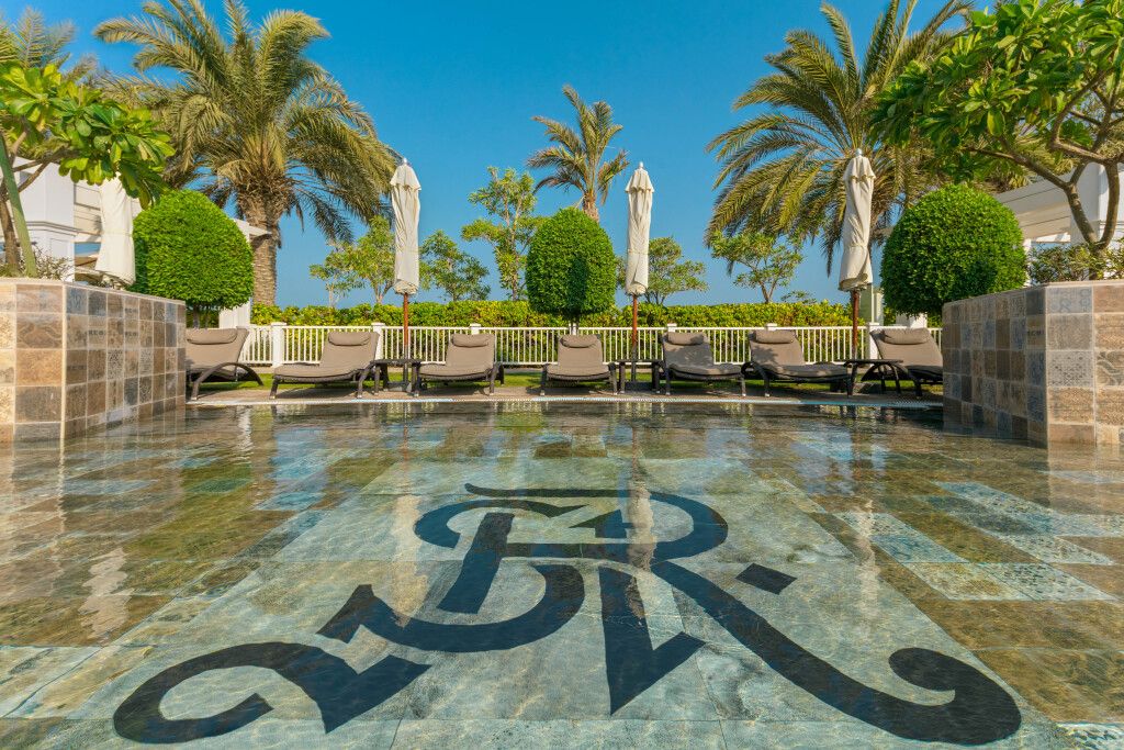 Luxuriöser Poolbereich mit Liegestühlen und Palmen im The St. Regis Abu Dhabi