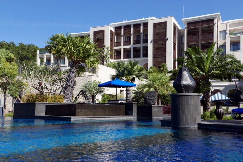 Luxuriöser Außenpool mit Palmen und moderner Hotelarchitektur im Hintergrund