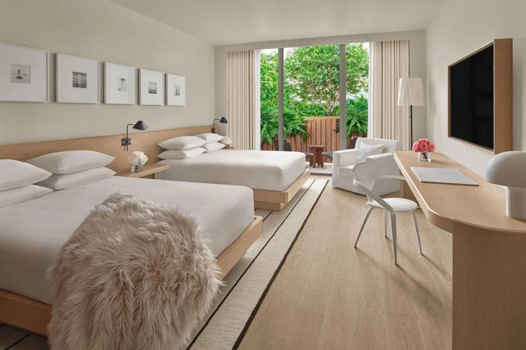 Modernes Hotelzimmer mit zwei Betten und großen Fenstern mit Blick auf eine Terrasse