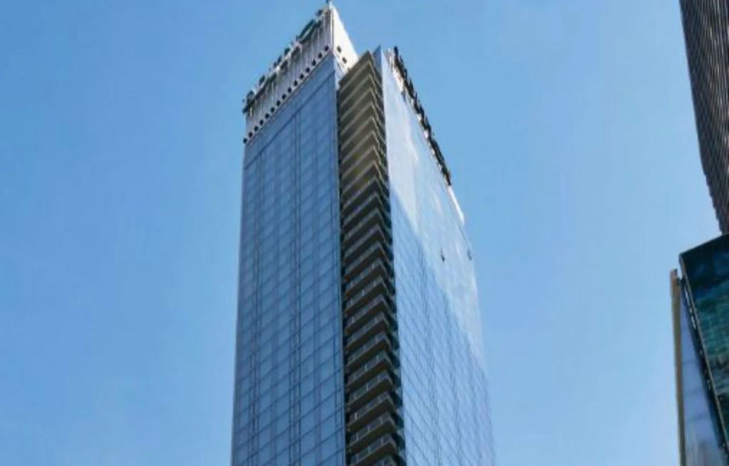 Modernes, hohes Gebäude des Times Square EDITION Hotels vor blauem Himmel.