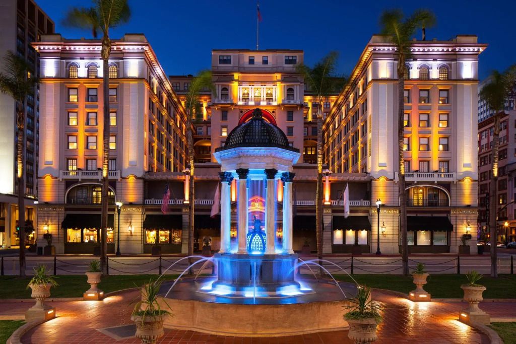 Historische Architektur der Vorderseite des US Grant Hotels beleuchtet bei Nacht mit Brunnen im Vordergrund.