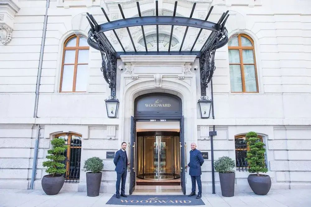Eingang des The Woodward Hotels mit eleganter Glasüberdachung und Portiers.