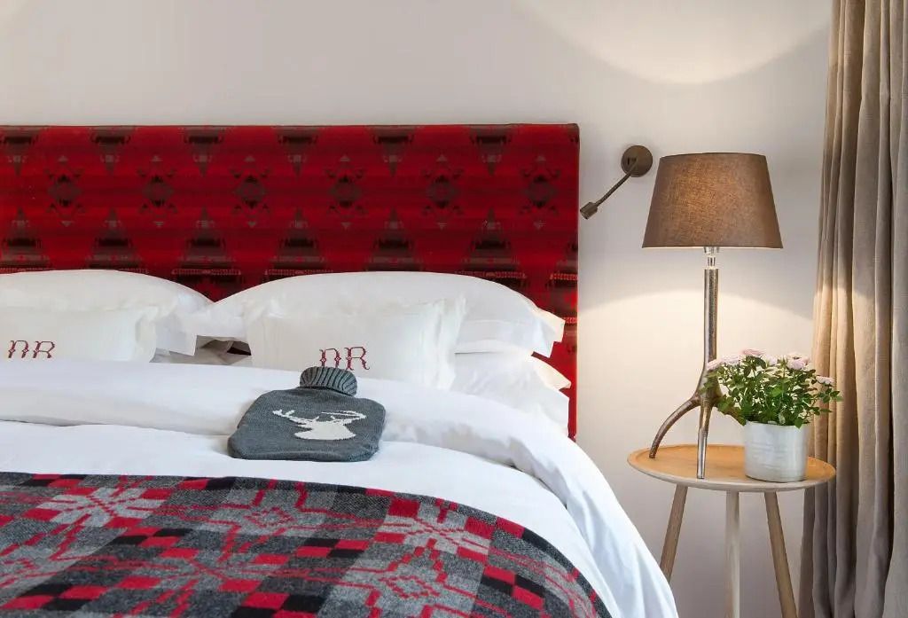 Gemütliches Hotelzimmer mit rotem Kopfteil und rustikaler Dekoration