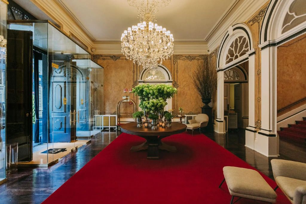 Elegante Lobby mit Kronleuchter und rotem Teppich im Torel Palace Porto