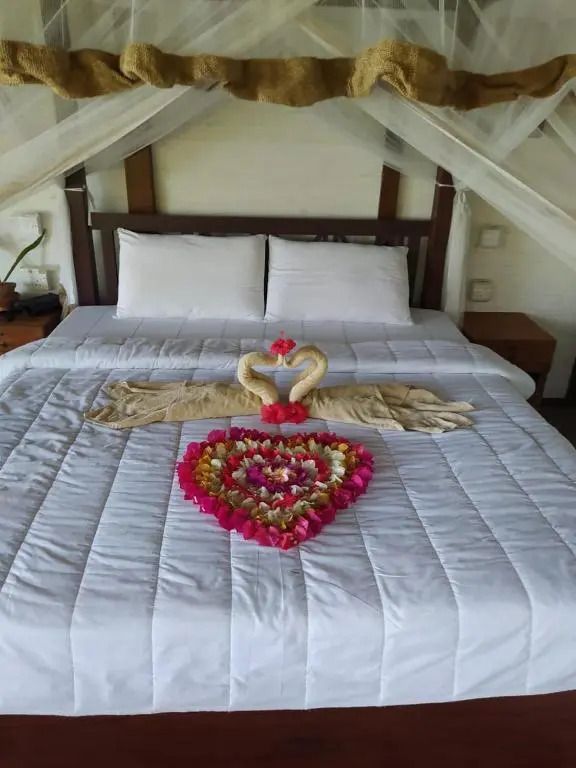 Zimmer mit dekoriertem Bett und Herz aus Blumenblüten