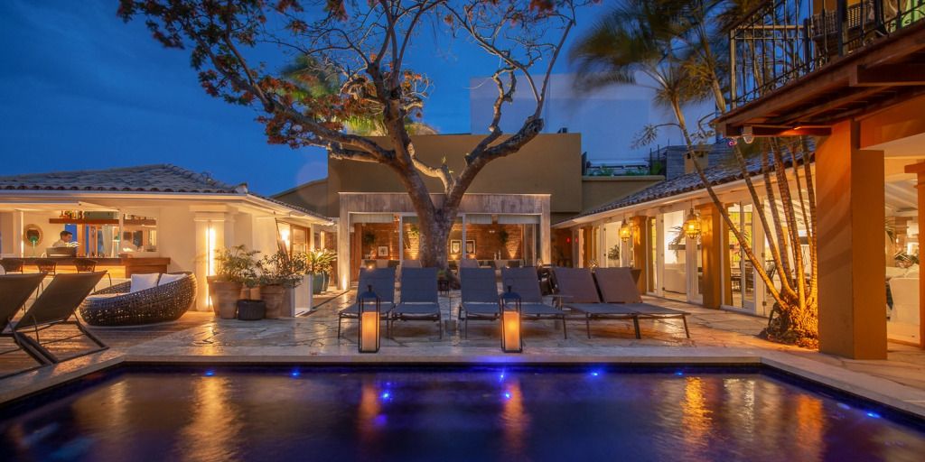 Beleuchtete Terrasse mit Liegestühlen am Pool und Baum im Abendlicht