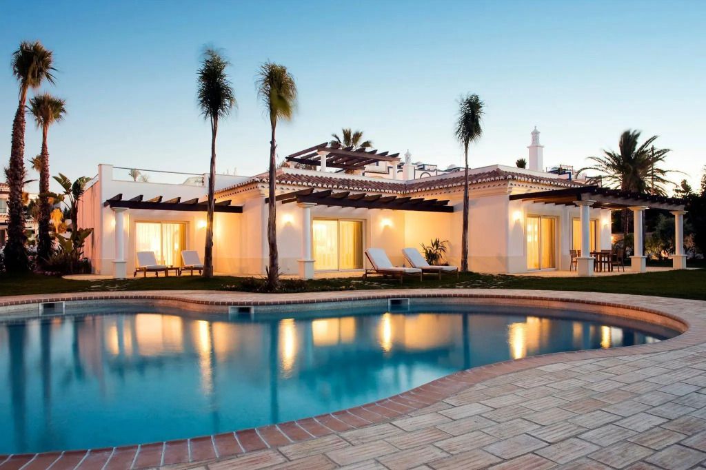 Luxusvilla mit Pool und exotischen Palmen bei Sonnenuntergang im Vila Vita Parc.