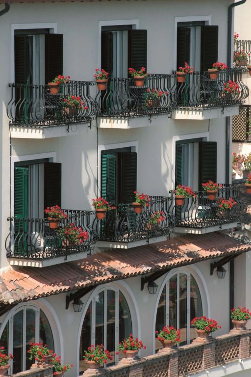 Fassade des Hotels mit charmanten Balkonen voller blühender Blumen.