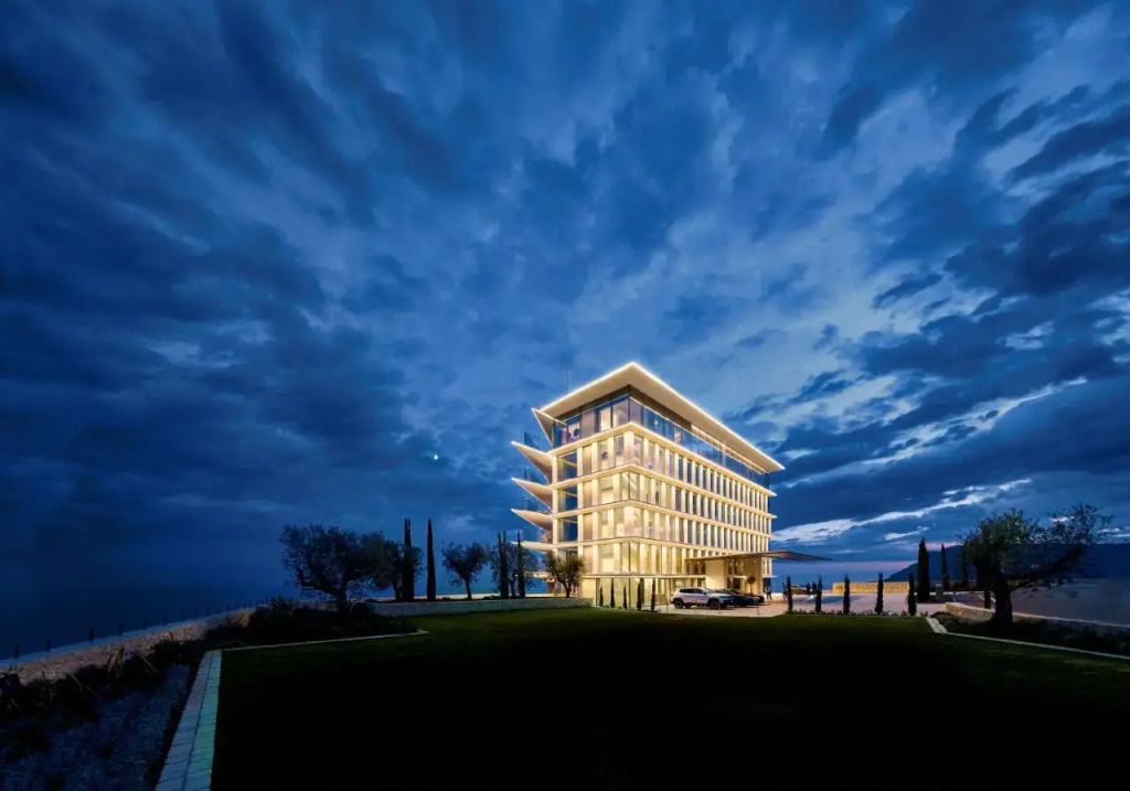 Beleuchtetes Hotelgebäude vor einem dramatischen Abendhimmel