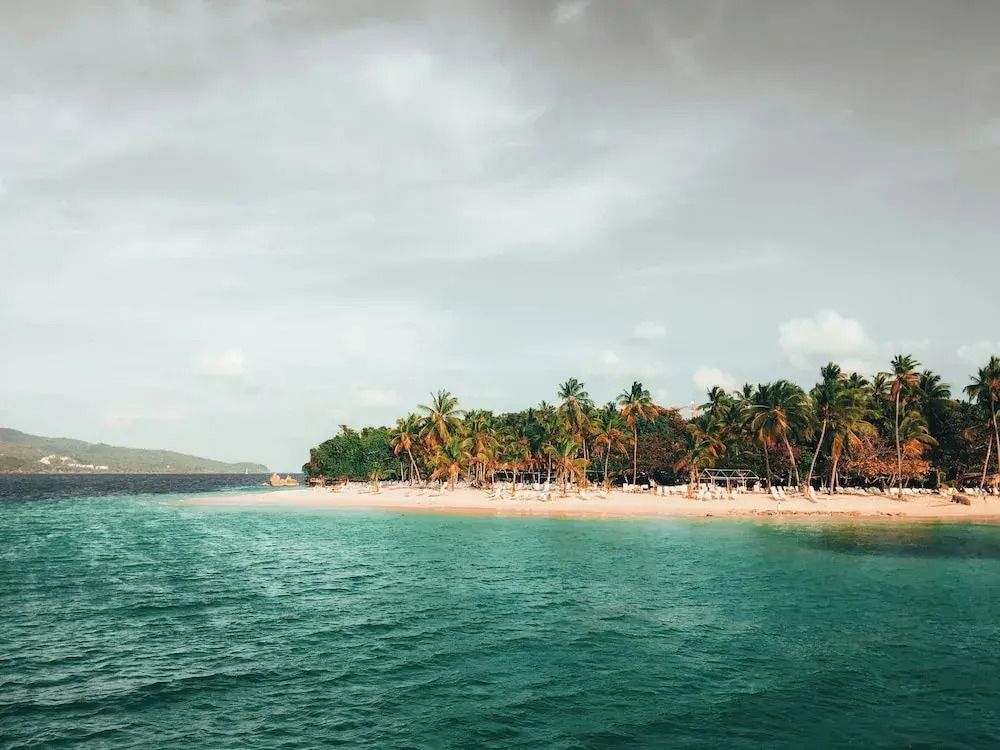 Strand mit Palmen und türkisfarbenem Wasser unter bewölktem Himmel