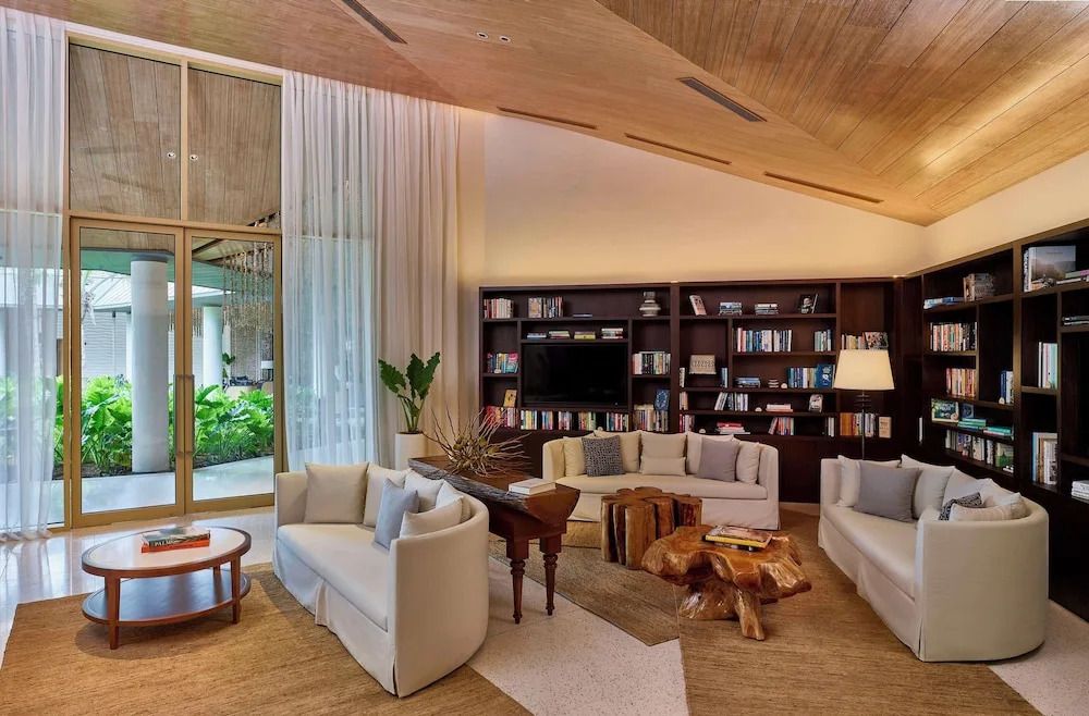 Elegante Hotel-Lounge mit Bücherregal und großen Fenstern mit Blick ins Grüne