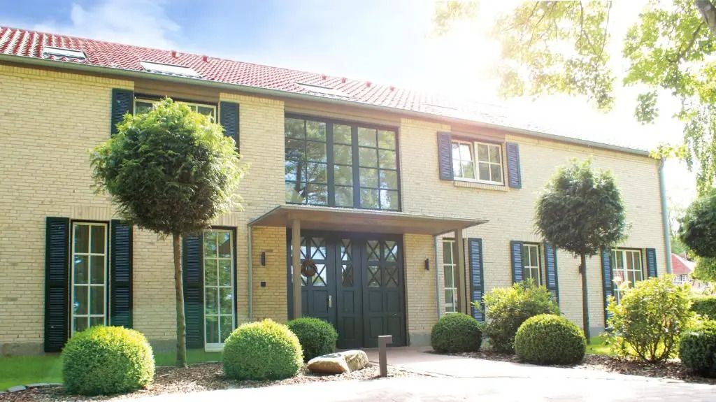 Elegante Fassade eines Landhauses mit gepflegtem Garten bei sonnigem Wetter