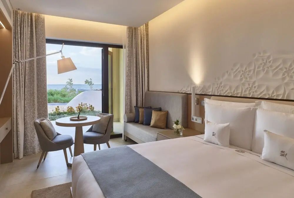 Helles Hotelzimmer mit Doppelbett und Blick auf die Terrasse